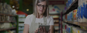 Mulher no corredor de um supermercado checando os itens no tablet