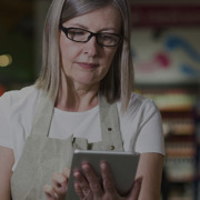 Mulher no corredor de um supermercado checando os itens no tablet