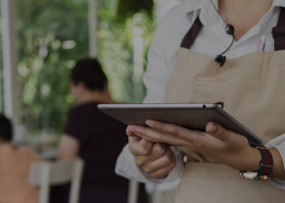 Mulher em um PDV segurando um tablet.