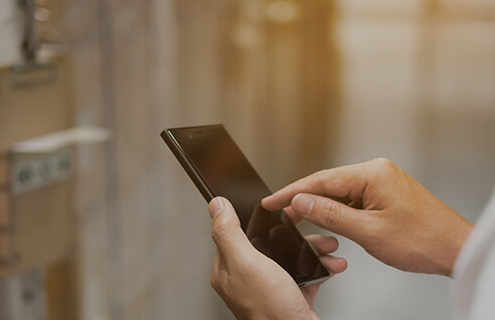 Vendedor segurando um smartphone enquanto acessa informações