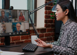 Imagem de uma mulher em frente ao computador em uma videoconferencia