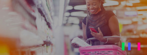 Foto de mulher no supermercado com uma cesta cheia de produtos e um celular na mão