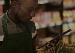 Homem mexendo no tablet dentro de um supermercado