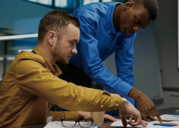 Dois homens no escritório analisando os erros no papéis em cima da mesa