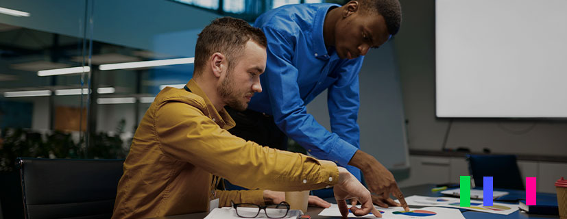 Dois homens no escritório analisando os erros no papéis em cima da mesa