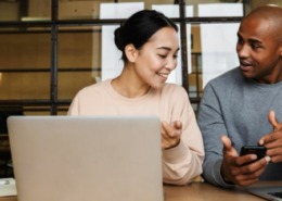 Homem e mulher sentando em frente a mesa do escritório conversando