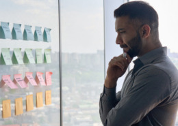 Homem analisando parede com post it.