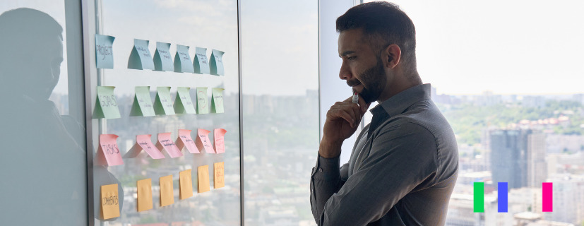 Homem analisando parede com post it.