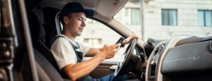 canais de distribuição logística - entregador dirigindo caminhão e olhando no celular